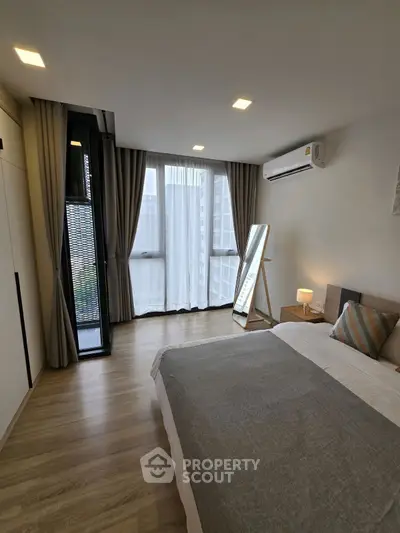 Modern bedroom with large windows and stylish decor in a high-rise apartment.