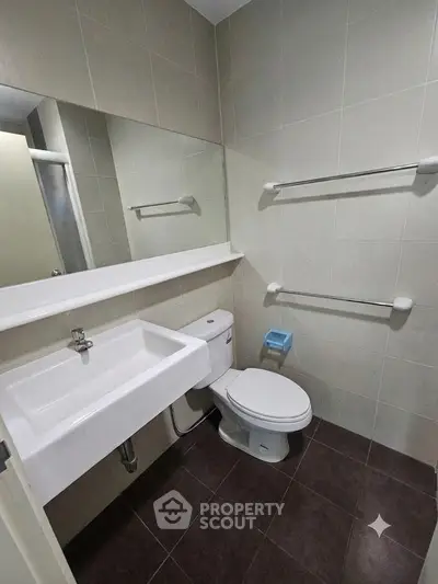 Modern bathroom with sleek fixtures and neutral tiles, featuring a wall-mounted sink and toilet.