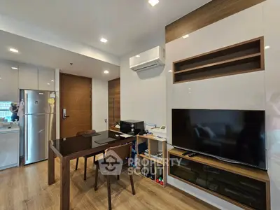 Modern living room with sleek furniture and integrated kitchen area, featuring a large TV and air conditioning.
