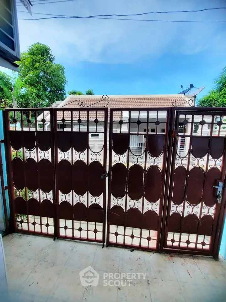 Charming gated entrance with decorative ironwork and lush greenery