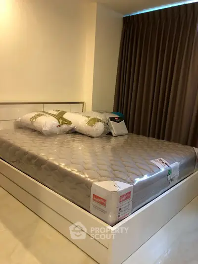 Modern bedroom with new mattress and pillows, featuring elegant curtains and sleek flooring.