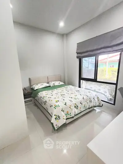 Cozy bedroom with modern decor and large window offering natural light.