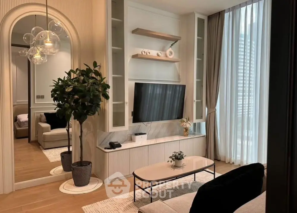 Stylish modern living room with large TV, elegant decor, and natural light.