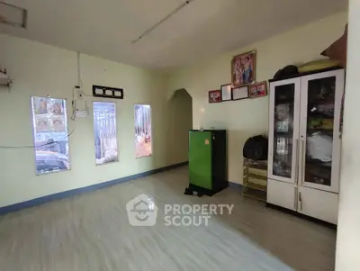 Spacious living room with modern flooring and ample natural light, featuring a storage cabinet and wall decor.