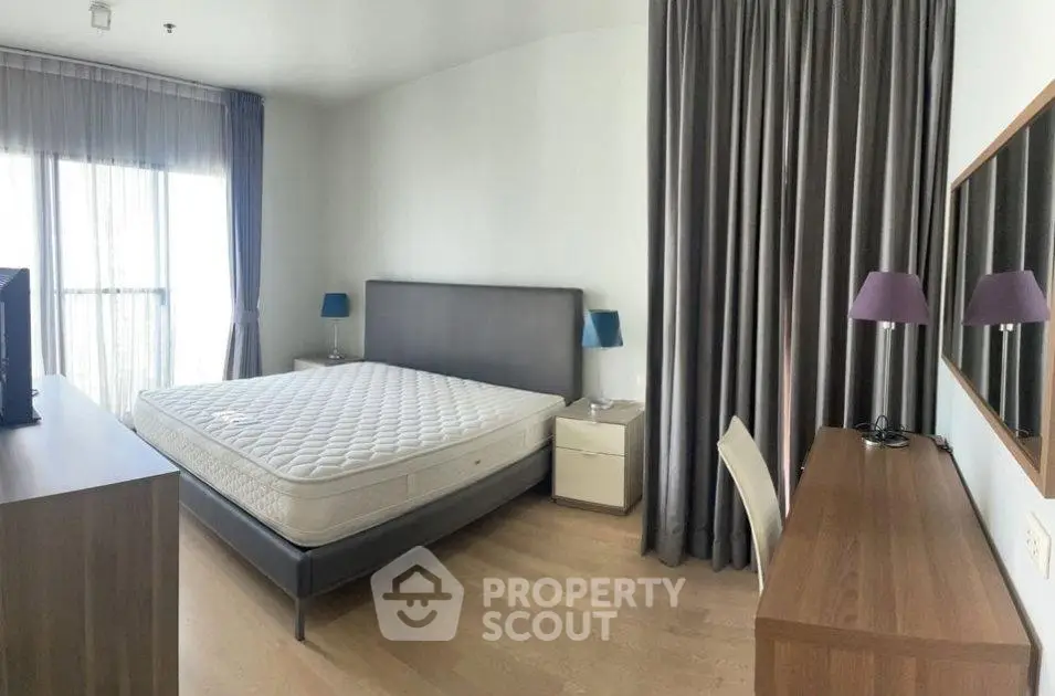 Spacious bedroom with modern furnishings and large window for natural light.