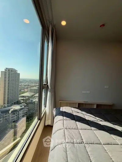 Spacious bedroom with stunning city view from large window, modern decor, and ample natural light.