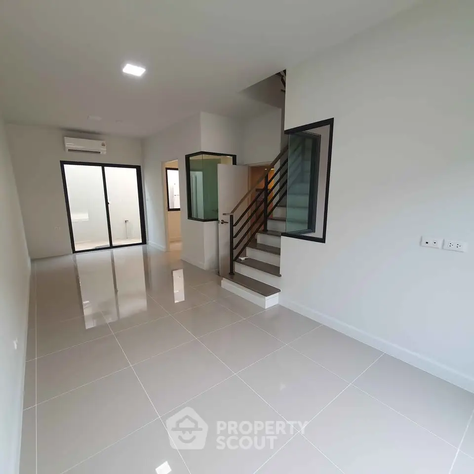 Modern minimalist interior with sleek staircase and glossy tiled flooring in a bright open space.
