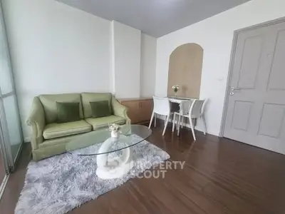 Charming living room with modern decor, featuring a cozy green sofa, glass coffee table, and elegant dining area.