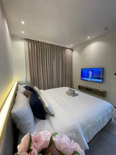 Luxurious bedroom with modern decor and wall-mounted TV, perfect for relaxation.