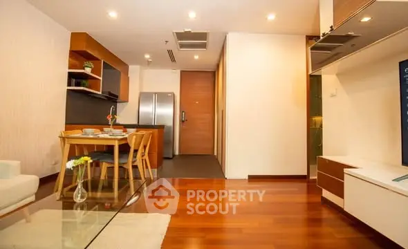 Modern open-plan living room with sleek kitchen and dining area, featuring wooden flooring and contemporary decor.