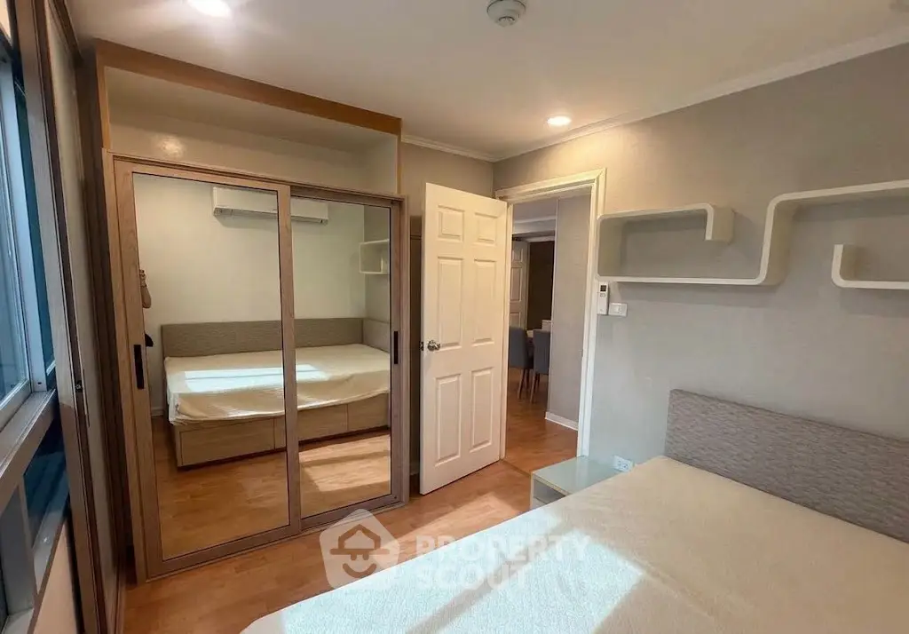 Cozy bedroom with mirrored wardrobe and modern decor in a stylish apartment.