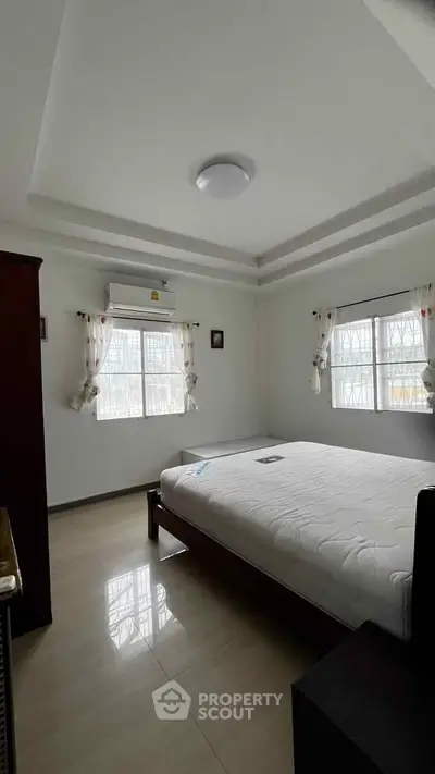 Spacious bedroom with natural light and modern decor in a serene setting.