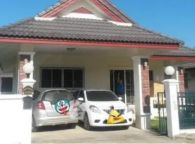 Charming suburban home with driveway and two cars, featuring a tiled roof and welcoming entrance.