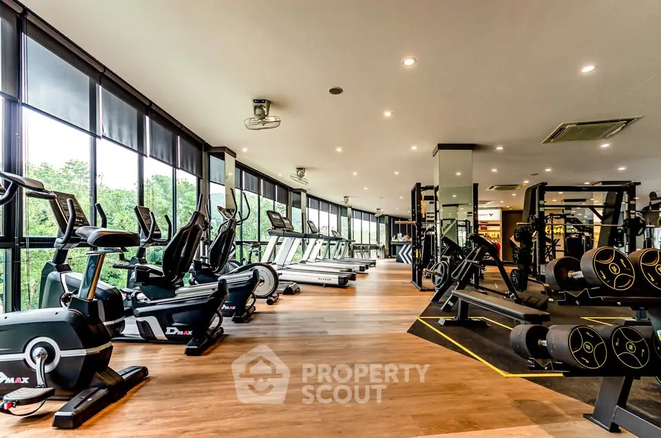 Spacious modern gym with state-of-the-art equipment and large windows offering scenic views.
