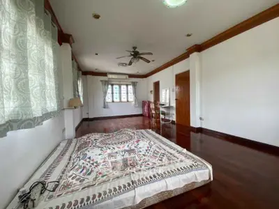 Spacious bedroom with wooden flooring and large windows in a cozy home.