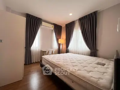 Cozy bedroom with large windows and elegant curtains, featuring a comfortable bed and warm lighting.
