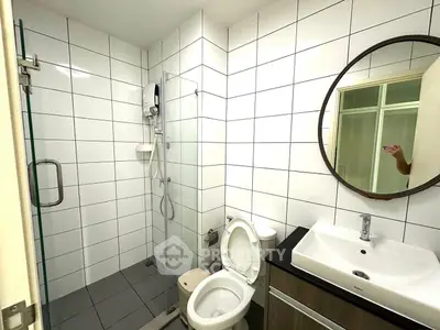 Modern bathroom with glass shower, round mirror, and sleek vanity in contemporary apartment.