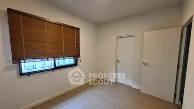 Spacious empty room with wooden blinds and modern flooring, perfect for customization.