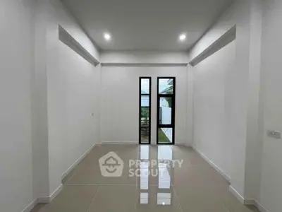 Spacious minimalist room with large windows and glossy tiled floor, perfect for modern living.