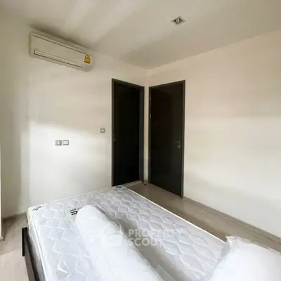 Minimalist bedroom with air conditioning and twin mattresses, ideal for modern living.
