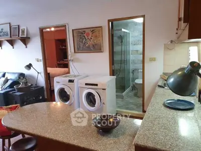 Cozy open-plan kitchen with washing machines and modern bathroom view