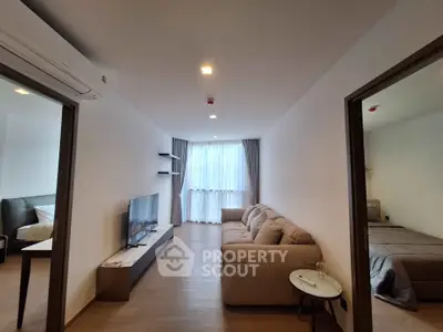 Modern living room with cozy sofa and flat-screen TV, adjacent to stylish bedrooms, featuring elegant decor and natural light.