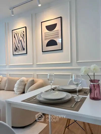 Stylish modern living room with elegant dining setup and chic wall art.