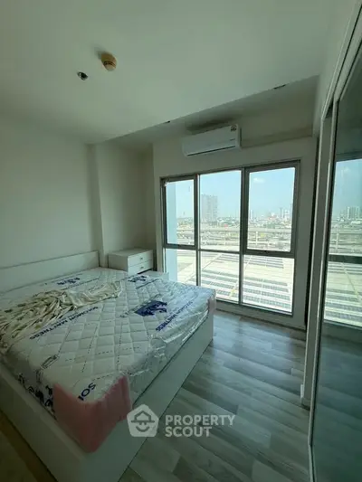 Bright bedroom with large windows offering stunning city views, featuring modern decor and ample natural light.