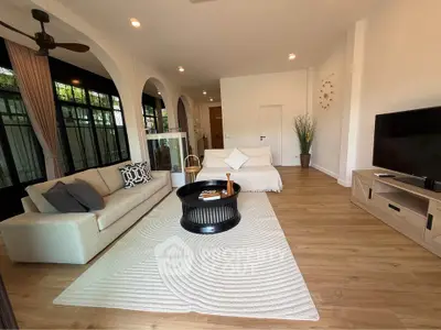 Spacious living room with modern decor and natural light, featuring a cozy sofa and stylish coffee table.