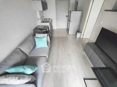 Modern compact living room with sleek furniture and open kitchen layout.