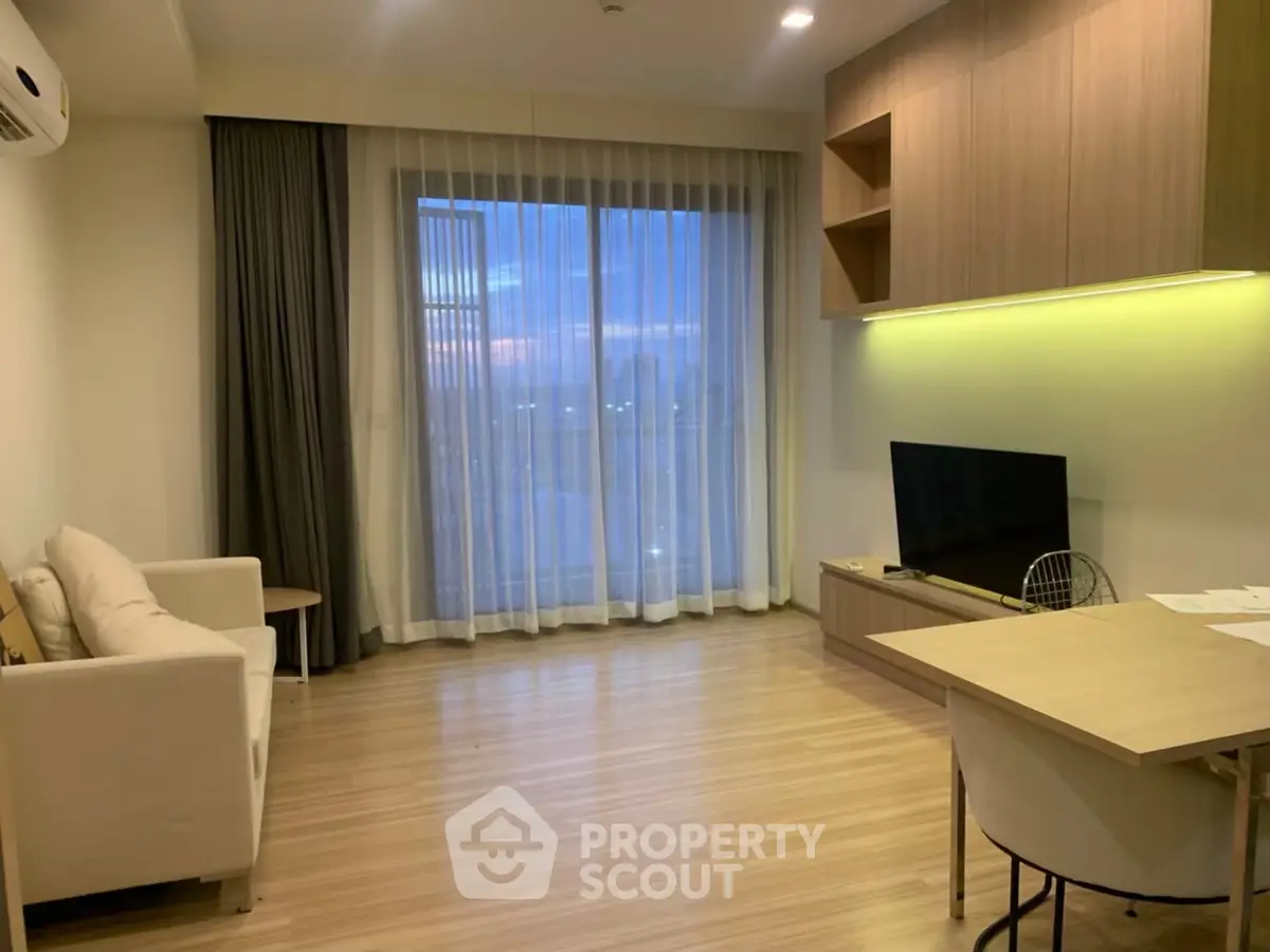 Modern living room with wooden flooring, cozy sofa, and large window view.