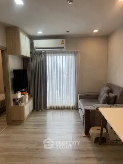 Modern living room with sleek design and natural light, featuring a cozy sofa and wall-mounted TV.