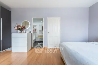 Spacious bedroom with modern decor and ensuite bathroom, featuring sleek wooden flooring and elegant furnishings.