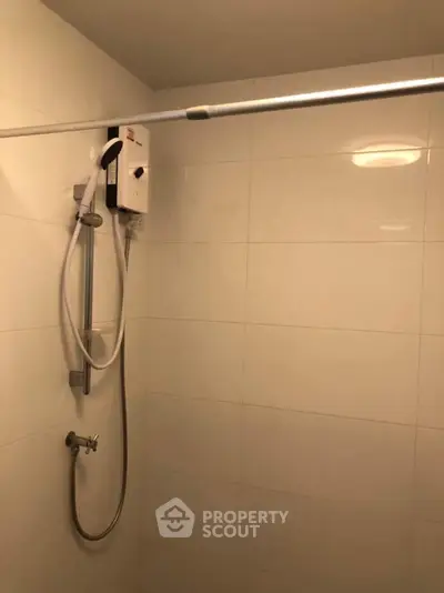 Modern bathroom with sleek shower setup and tiled walls, perfect for a contemporary home.