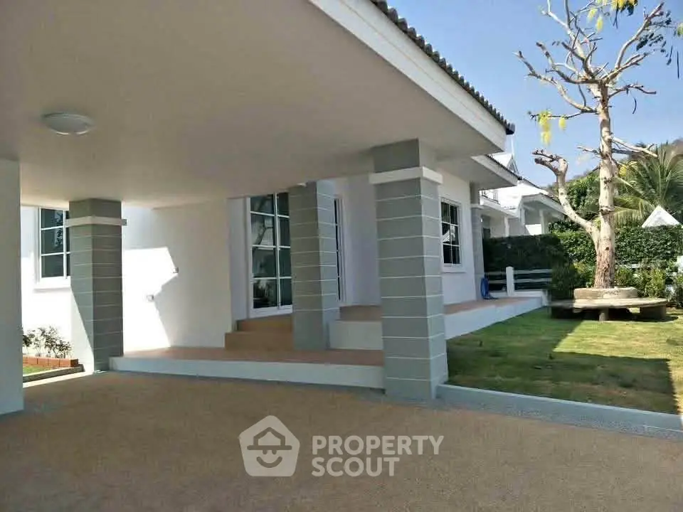 Charming modern house exterior with spacious covered patio and lush garden, perfect for outdoor relaxation.