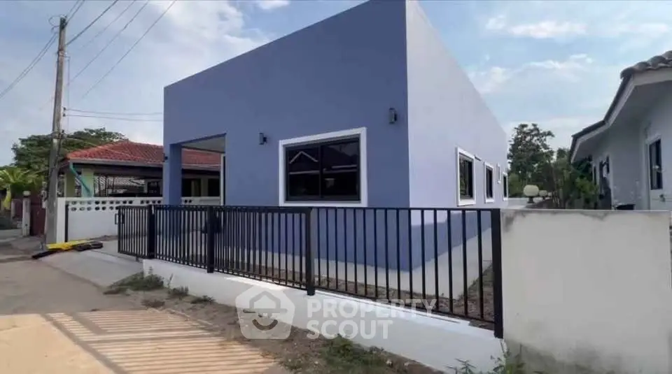 Modern blue single-story house with sleek black fence and minimalist design.