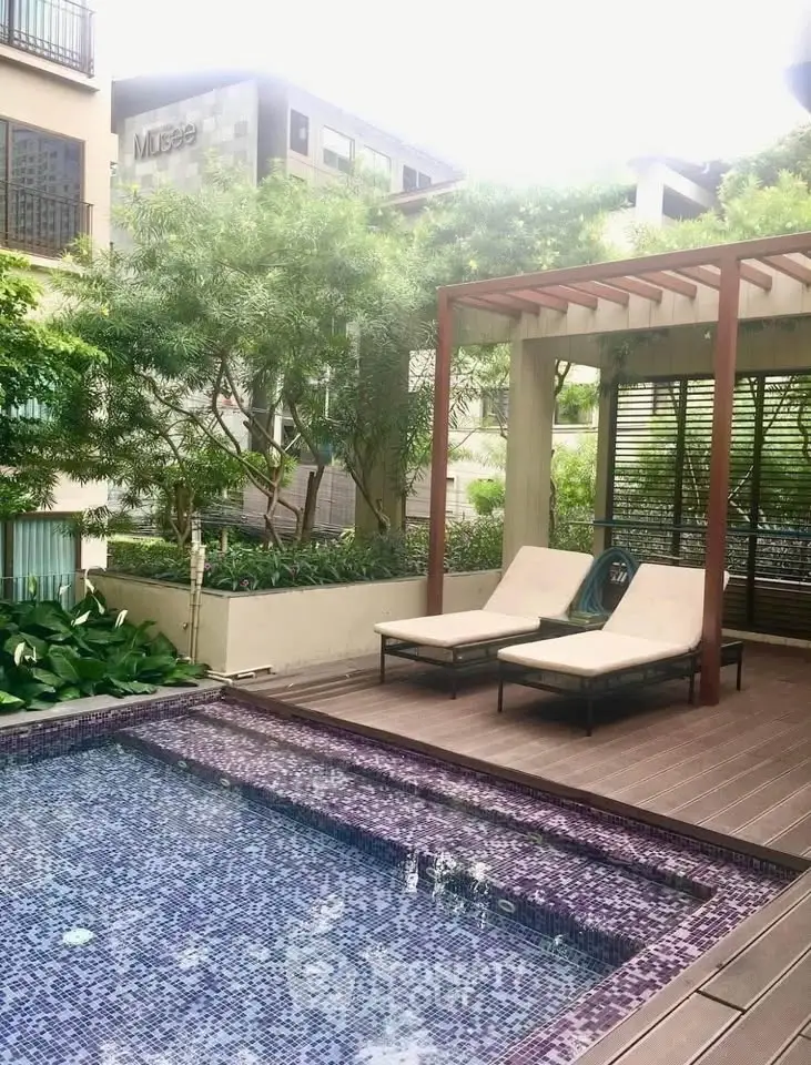 Luxurious outdoor pool area with modern lounge chairs and lush greenery in a high-end residential complex.