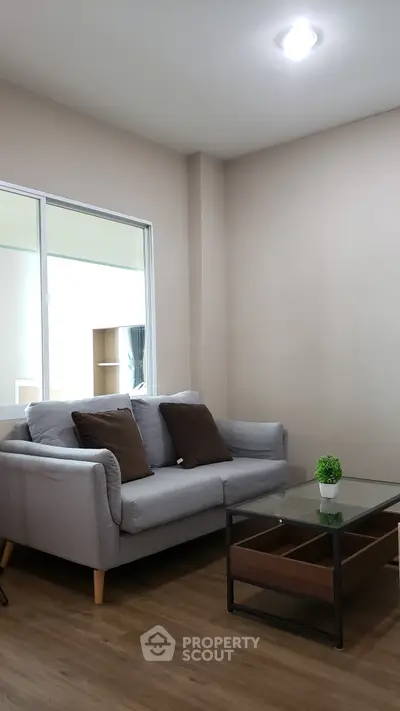 Cozy living room with modern gray sofa and glass coffee table, perfect for relaxation.