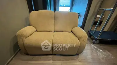 Cozy living room with a comfortable beige sofa and wooden flooring, perfect for relaxation.