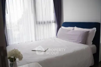 Cozy bedroom with large window and elegant decor, perfect for relaxation and comfort.