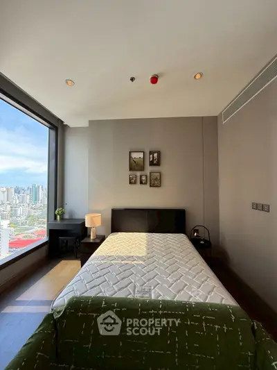 Modern bedroom with large window offering stunning city view, stylish decor, and cozy ambiance.