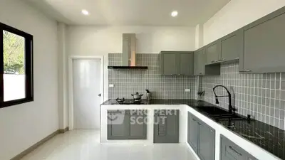Modern kitchen with sleek gray cabinets and black countertops in a bright, spacious layout.