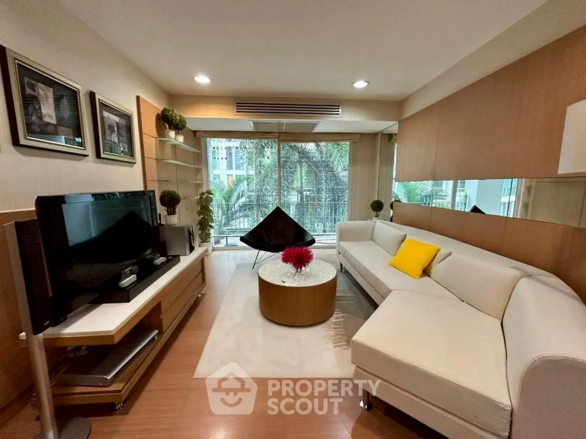 Modern living room with stylish decor and large windows overlooking greenery.