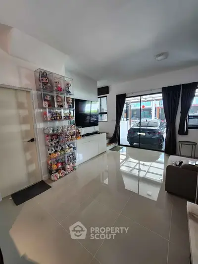 Spacious living room with modern decor and large window view of parked car outside.