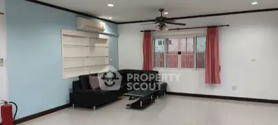 Spacious living room with modern black sofa and ceiling fan, perfect for relaxation.