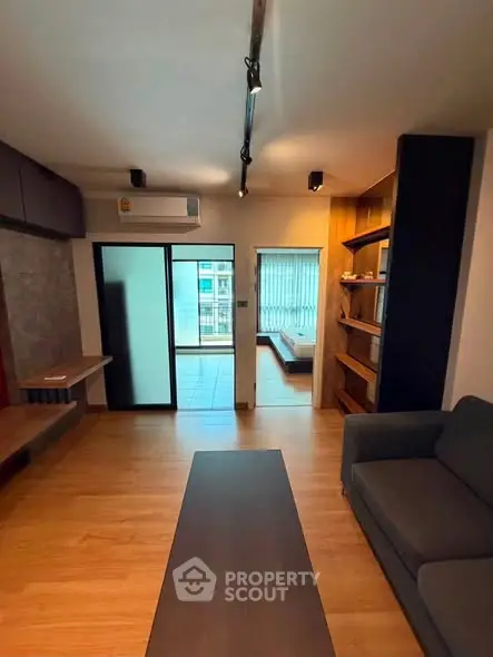 Modern living room with wooden flooring and balcony view in urban apartment