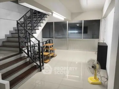 Spacious interior with modern staircase and large windows, ideal for versatile living space.
