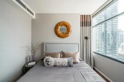 Modern bedroom with city view, stylish decor, and large windows in a high-rise apartment.