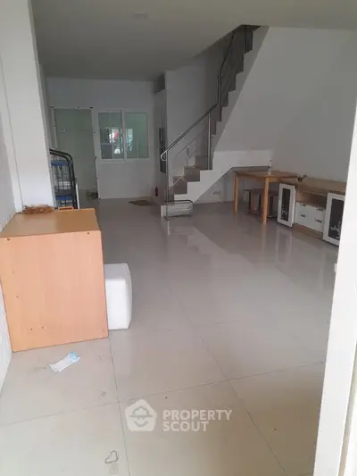 Spacious interior with modern staircase and glossy tiled flooring, ideal for versatile living arrangements.