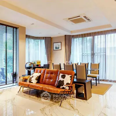 Luxurious open living and dining area with modern decor and large windows.